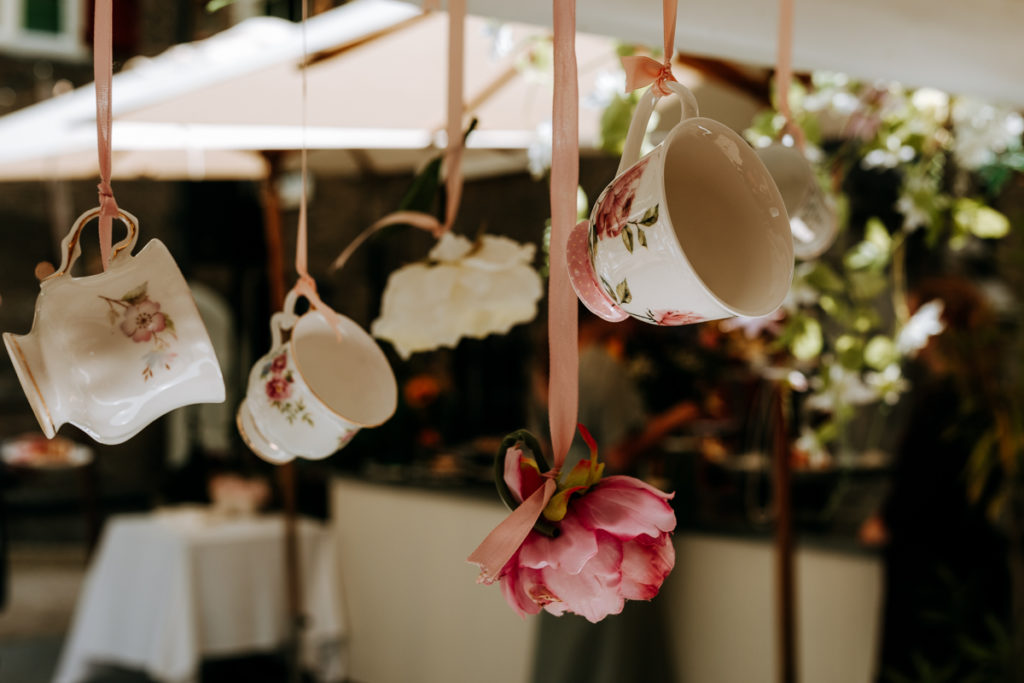 Oude engelse theekopjes hangen aan een lint tijdens de Royal High Tea bij museumcafe Gouda