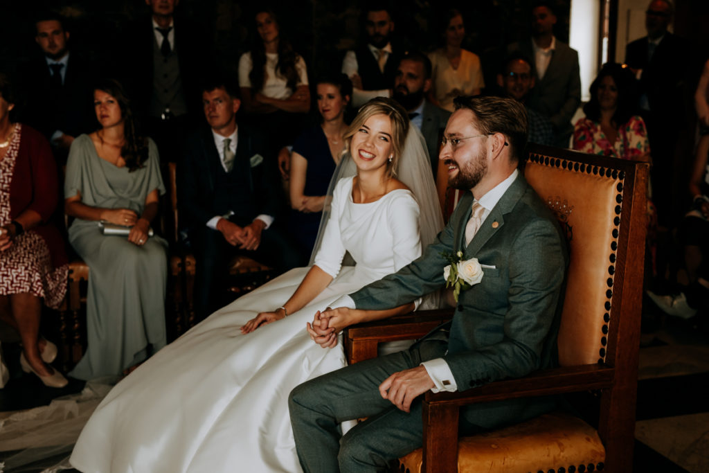 Bruid en bruidegom zitten op stoelen tijdens ceremonie in het stadhuis van Gouda.