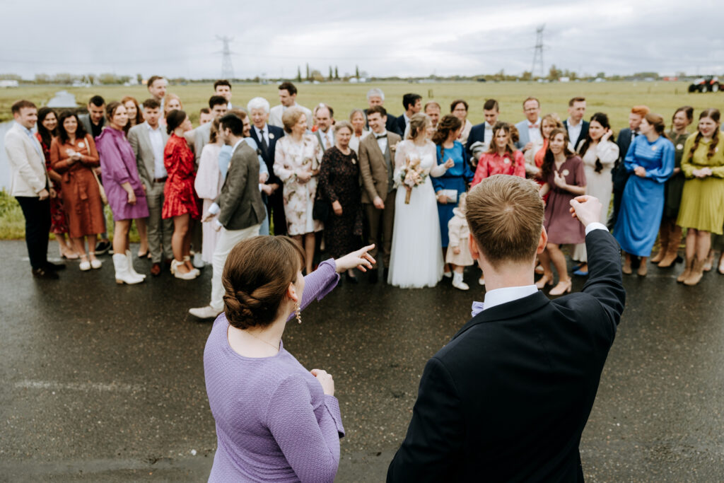 Twee ceremoniemeesters wijzen de gasten hun plek voor de groepsfoto