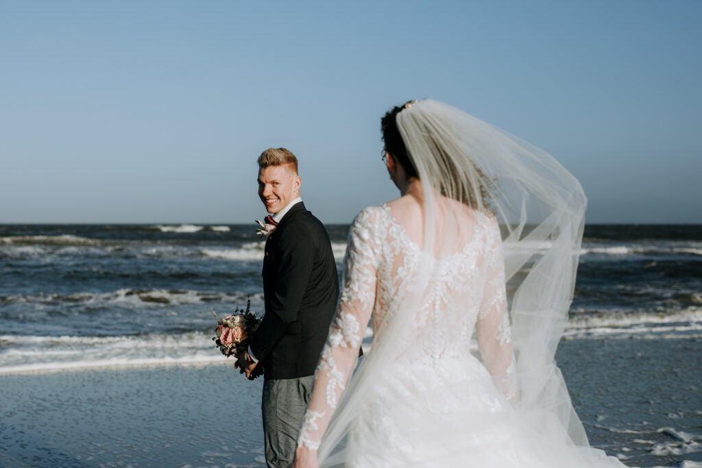 Bruidegom ziet zijn bruid voor het eerst op het strand bij de vloedlijn