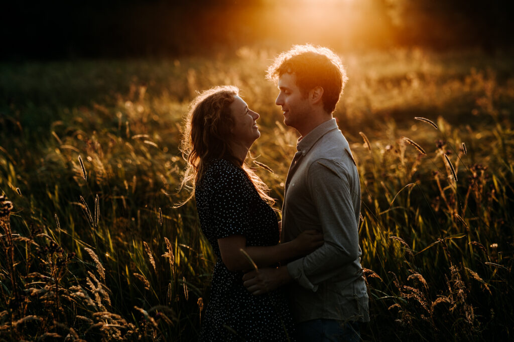 Stel dat poseert en elkaar aankijkt met goldenhour  tegenlicht