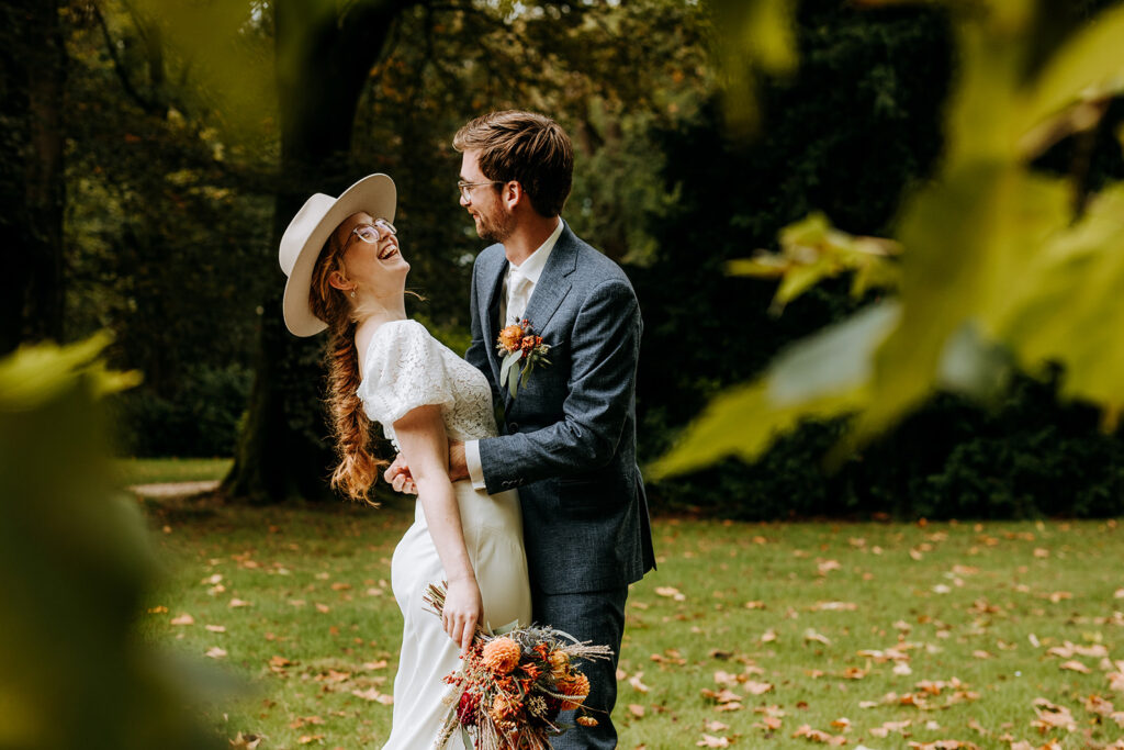 Bruid met hoed en bruidegom tijdens de fotoshoot in de herfst