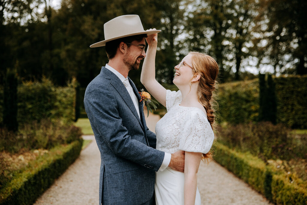 bruidgom heeft de hoed van de bruid op, ze lachen naar elkaar