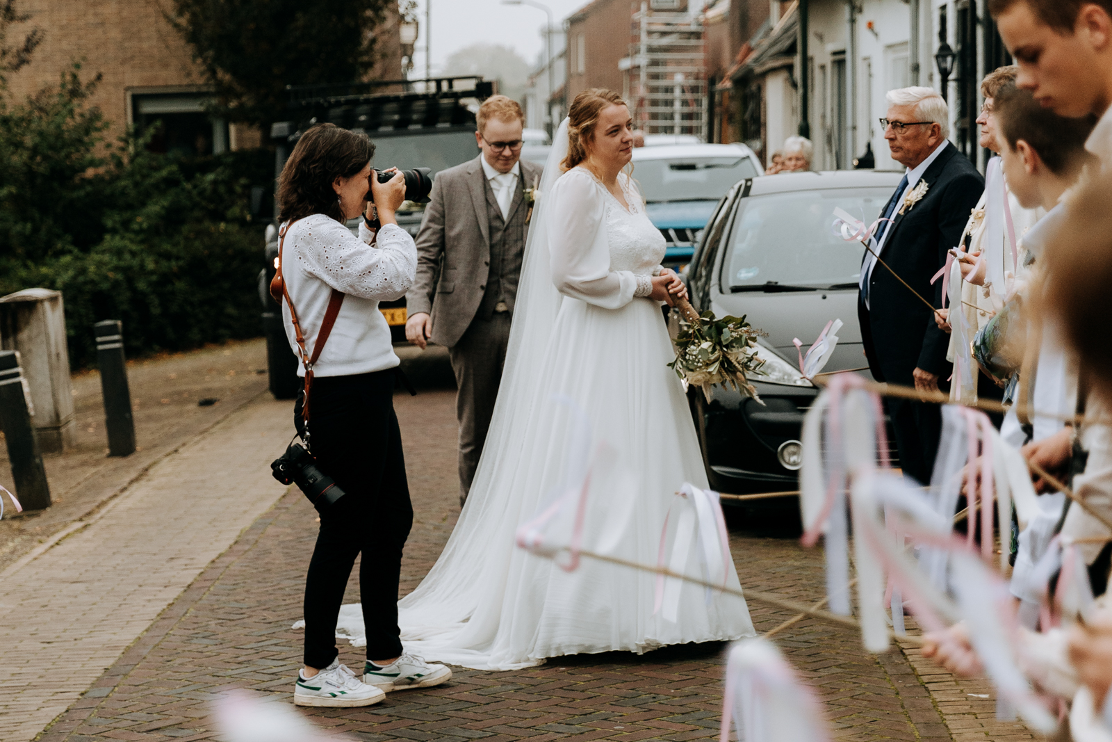 trouwfotograaf die onzichtbaar voelt maar toch dichtbij het bruidspaar staat te fotograferen