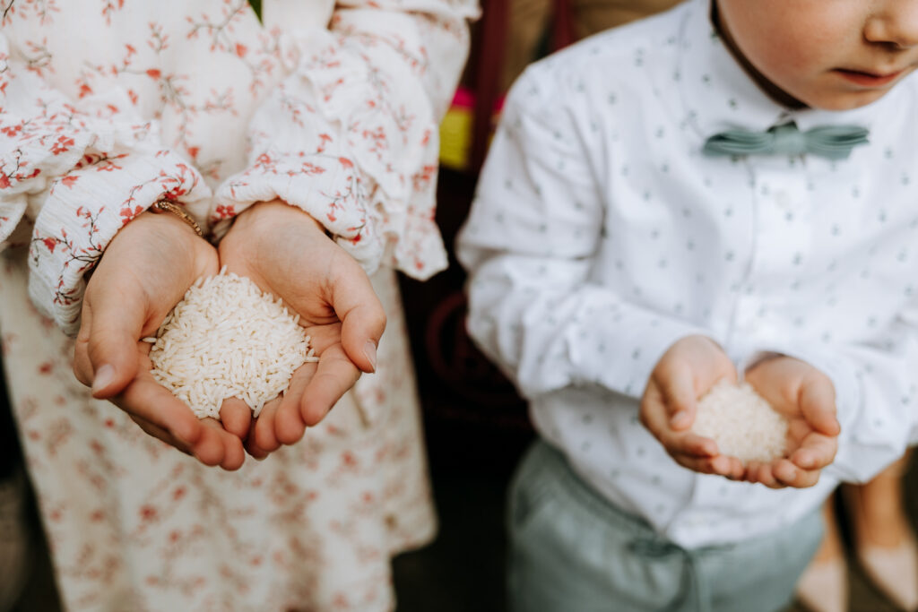 Twee kinderen met hun handen vol met rijst om naar het bruidspaar te gooien