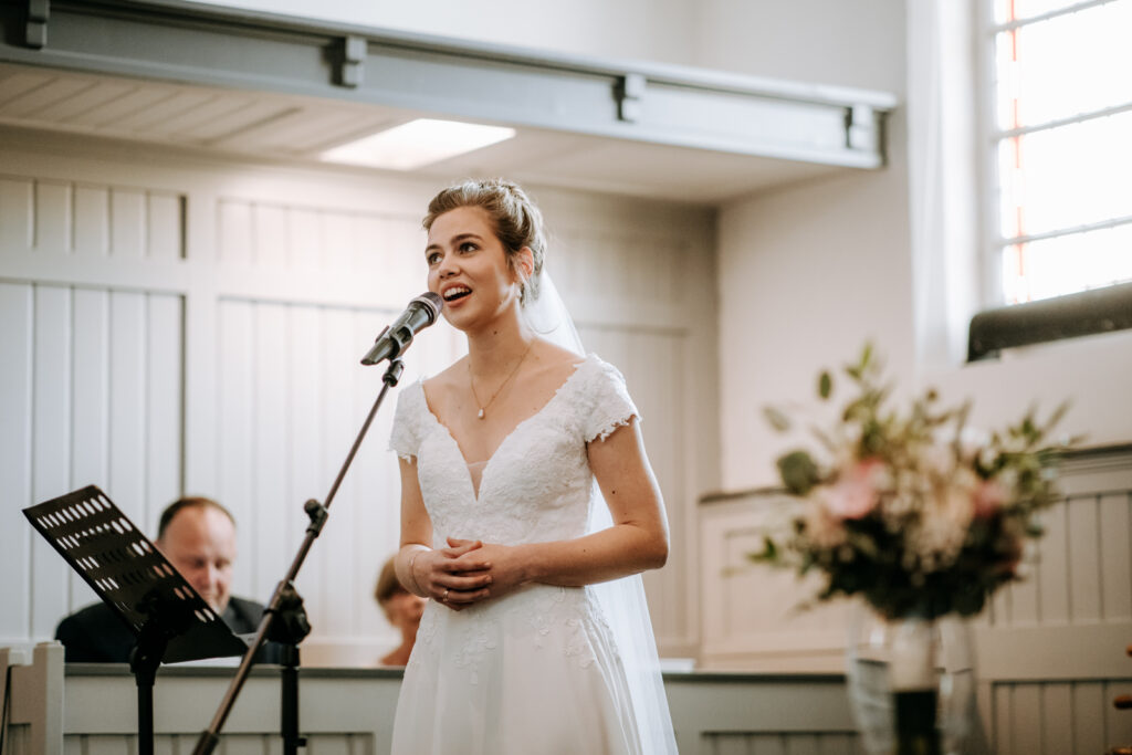 Bruid in witte trouwjurk zingt solo in de kerk