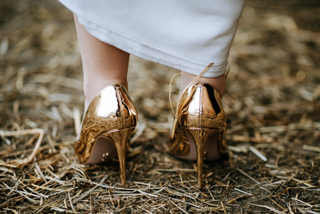 De gouden high heel pumps van de bruid, terwijl ze in het stro staat