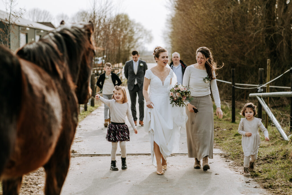 Bruid en vriendin en kind lopen langs een paard