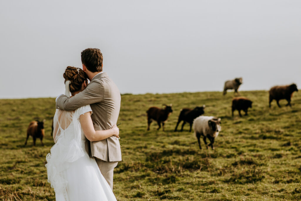 Bruid en bruidegom staan dicht tegen elkaar naar hun schapen te kijken