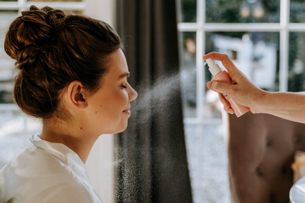 Bruid krijgt make-up spray en dat is mooi zichtbaar door het tegenlicht