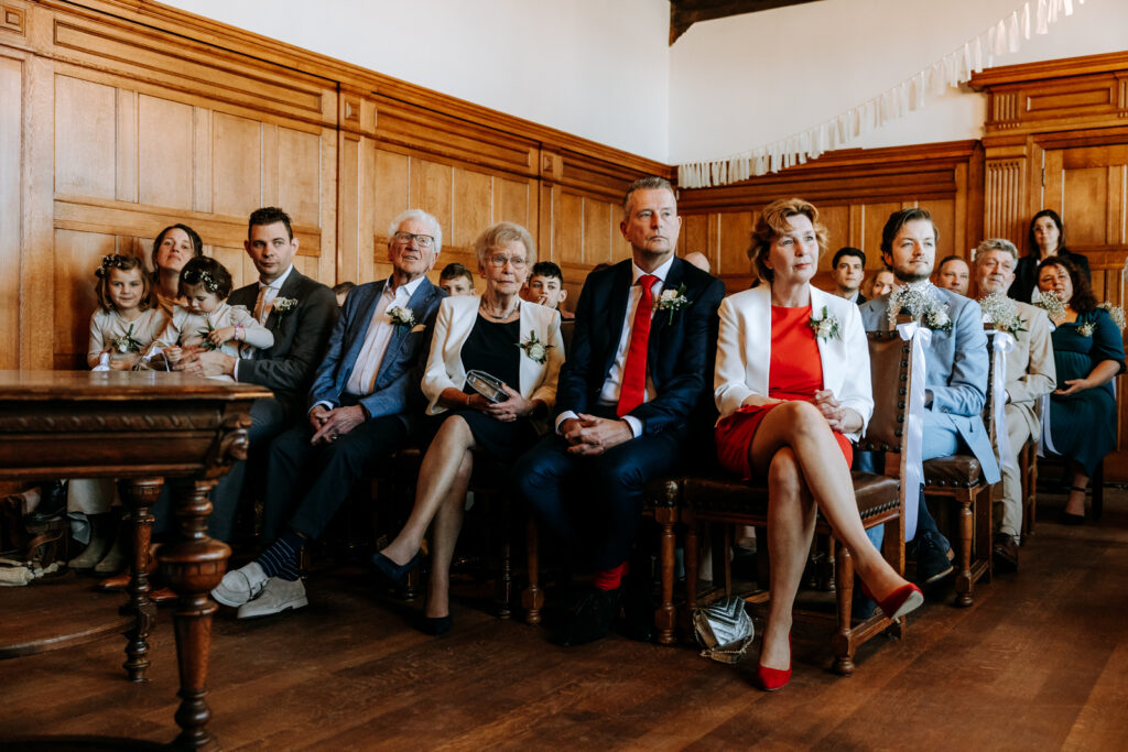 familieleden en vrienden van bruidspaar luisteren aandachtig tijdens de trouwceremonie