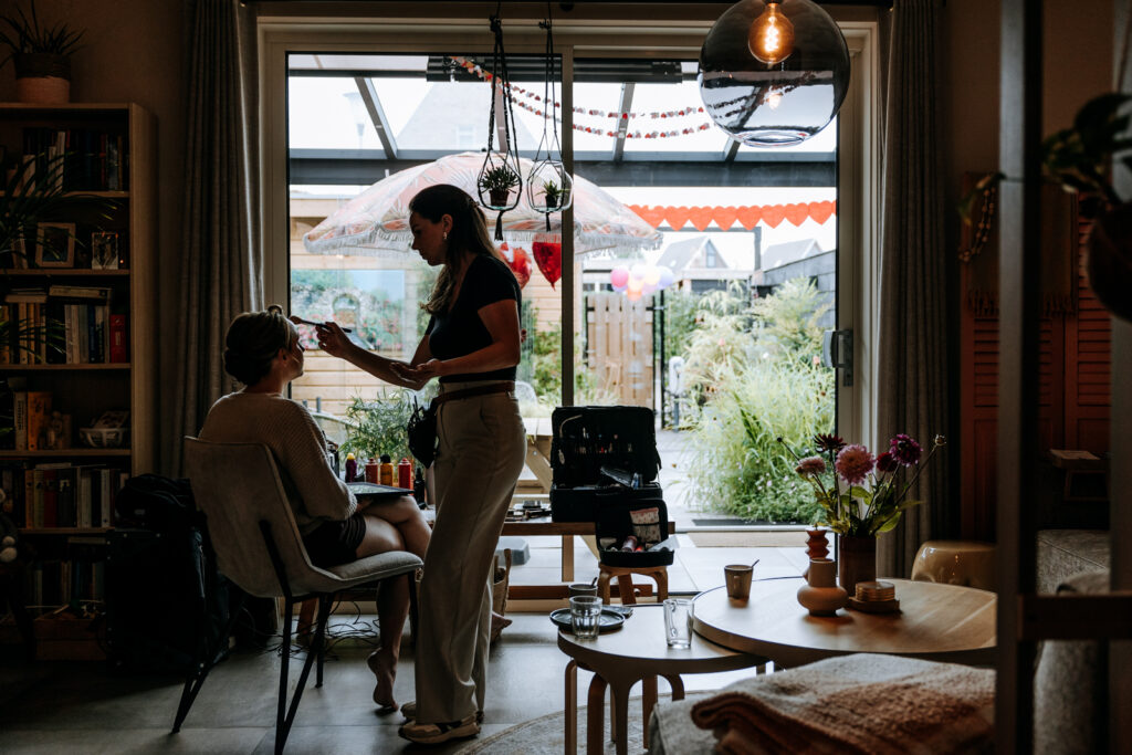 silhouet van bruid en Muah die haar make-up aanbrengt