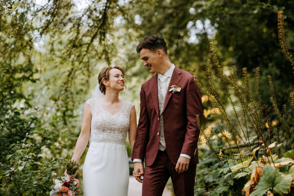 Bruidspaar loopt door groen park met veel bloemen, gefotografeerd door trouwfotograaf in Rotterdam
