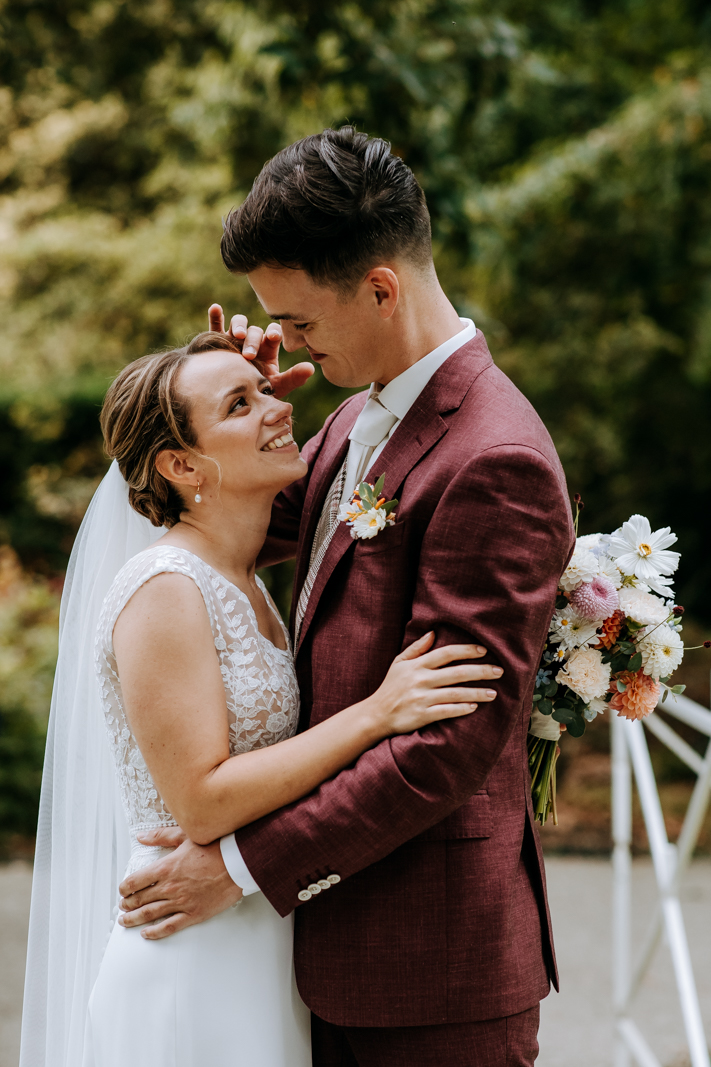 Bruidspaar knuffelt op bruggetje in park in Rotterdam