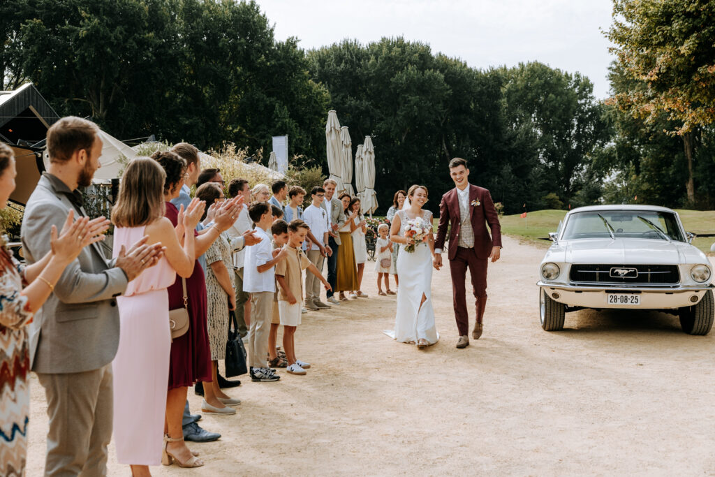 Bruidsgasten klappen terwijl het bruidspaar aan komt lopen