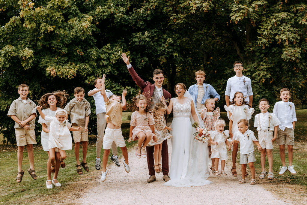 Bruidspaar en alle kinderen die gast zijn springen in de lucht