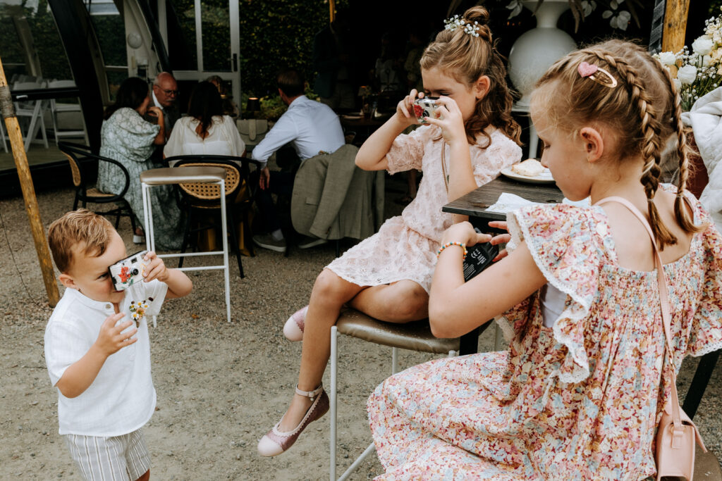 Kinderen die bruiloftsgast zijn fotograferen elkaar met wegwerpcamera's