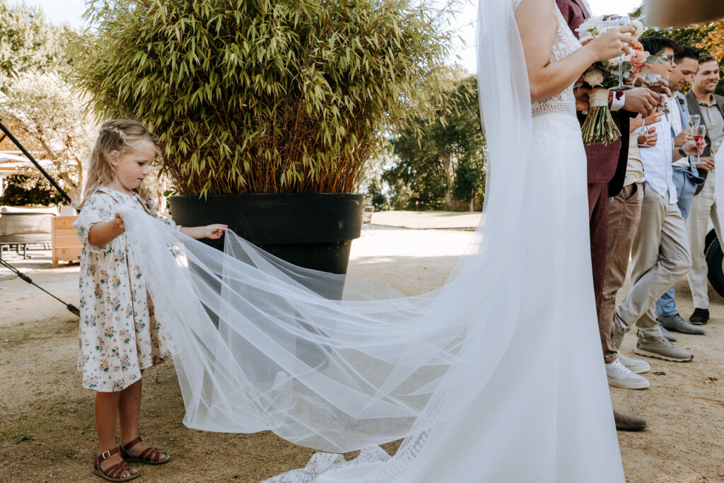 Meisje tilt sluier van de bruid op en kijkt er bewonderend naar