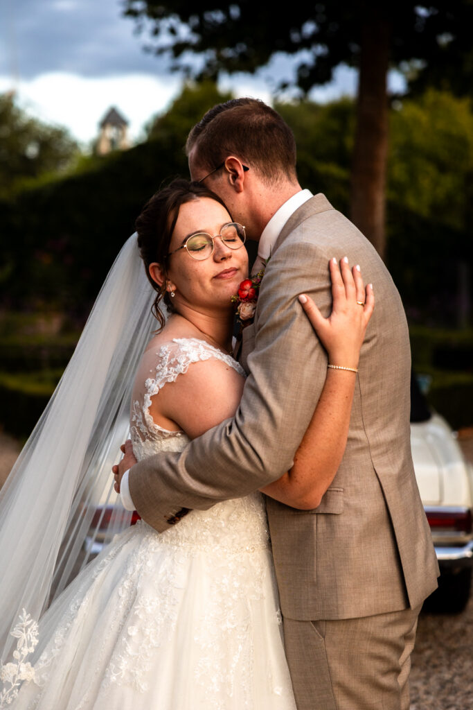 Dromerige, warme foto van het bruidspaar dat elkaar een liefdevolle knuffel geeft in het warme licht van het golden hour