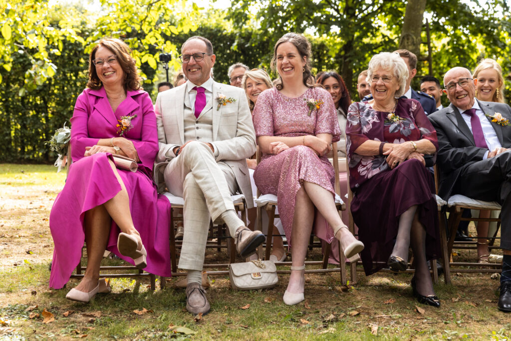 De vrolijke en kleurrijke eerste rij van de bruiloftsgasten, die hard moeten lachen om de speech van de babs