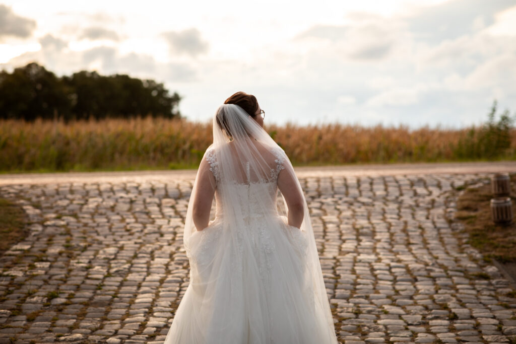 Moody fot van de bruid die richting de dijk loopt tijdens het golden hour