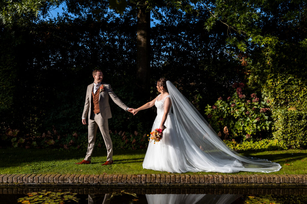 Bruid en bruidegom op weg naar de fotoshoot, bruidegom leidt de bruid aan de hand en kijkt naar haar
