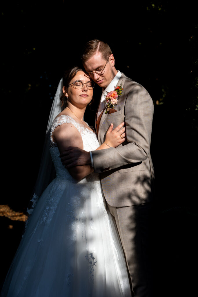 Bruid en bruidegom staan samen in de zon, ze sluiten hun ogen en genieten