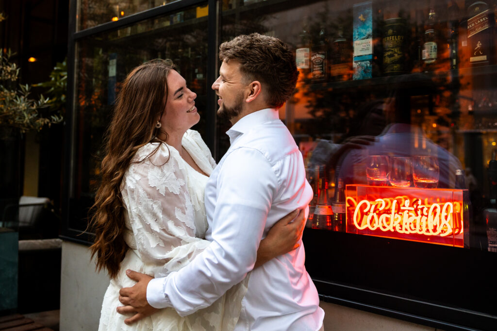 Koppel in Rotterdam tijdens een loveshoot voor een bar met een bordje met het opschrift "cocktails"